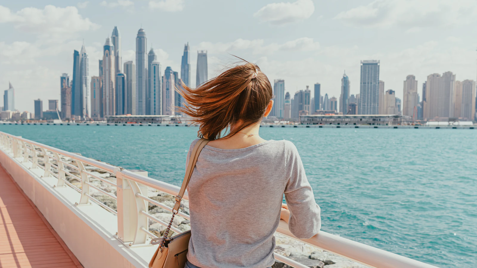 A woman looking out at the Dubai skyline from the waterfront