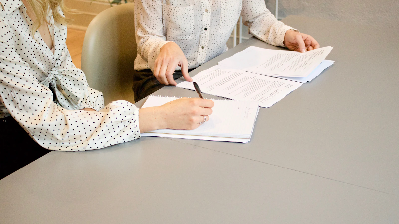 Two people reviewing and signing documents at a table