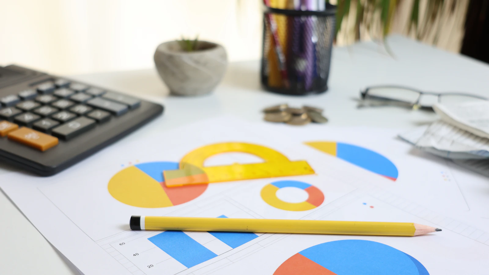 A calculator, pencil and colourful charts on a bright desk