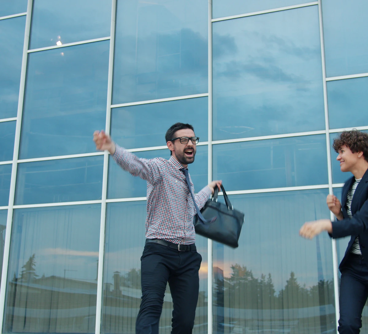 Two founders celebrating outside a glass office building