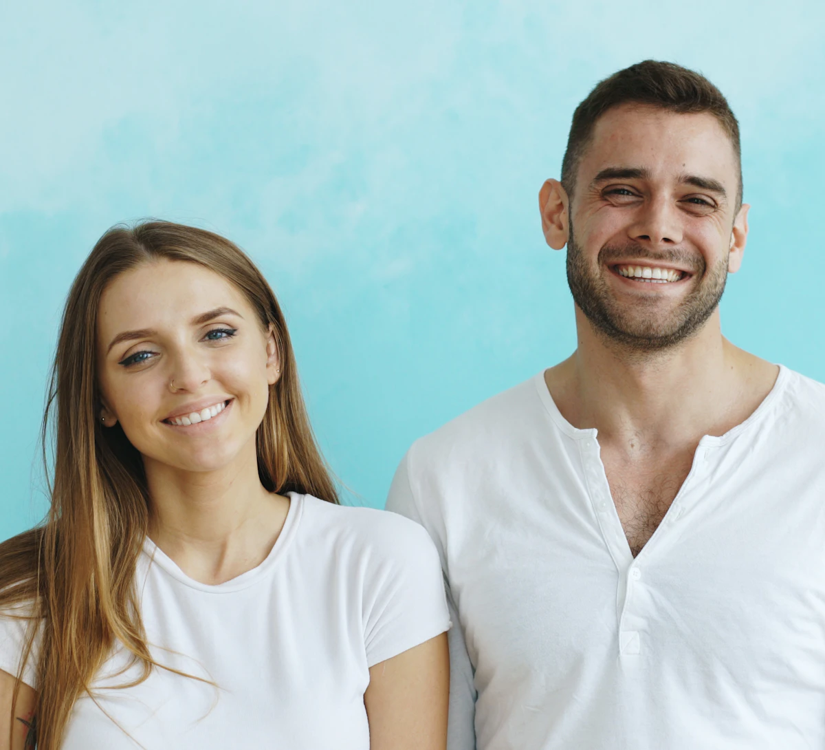 A smiling couple against a blue wall