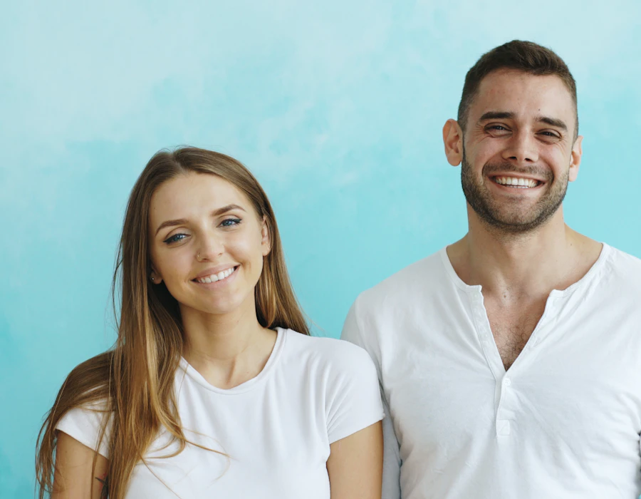 A smiling couple against a blue wall
