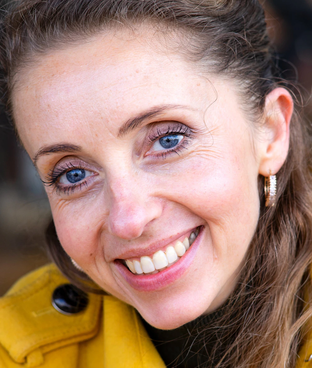 A smiling founder in a yellow coat