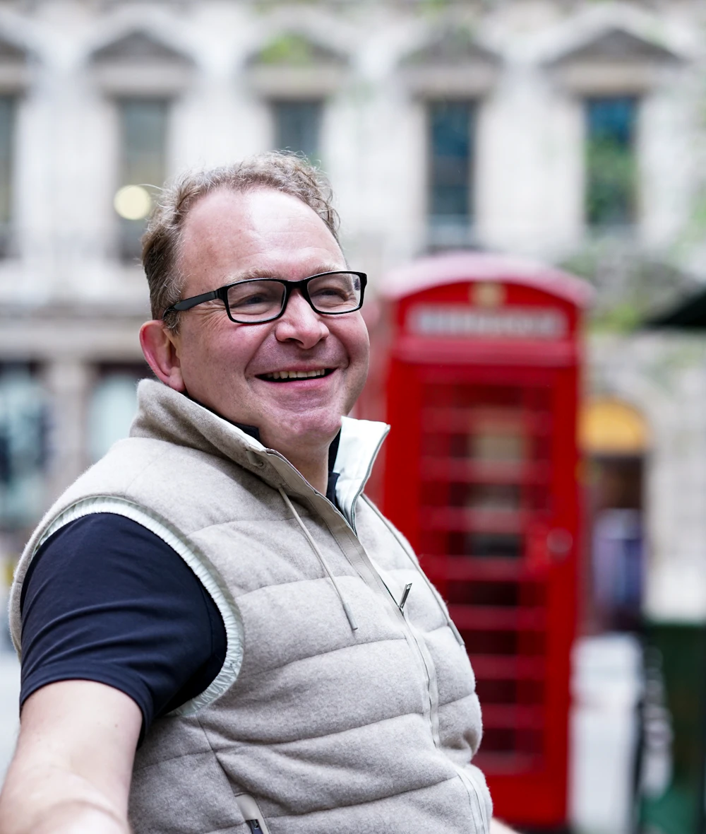 A smiling founder beside a red London phone box